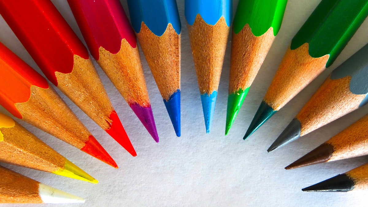 Colored pencils, in every color of the rainbow, spread out into a half circle.
