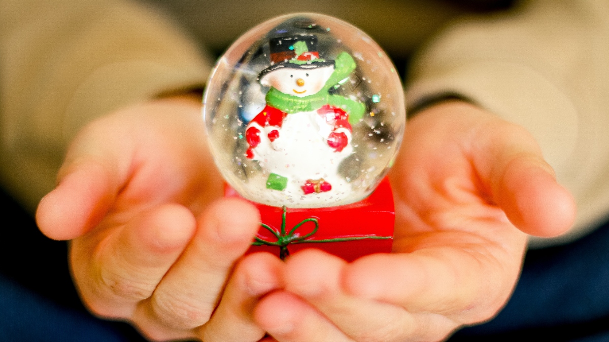 hands holding snowman snow globe