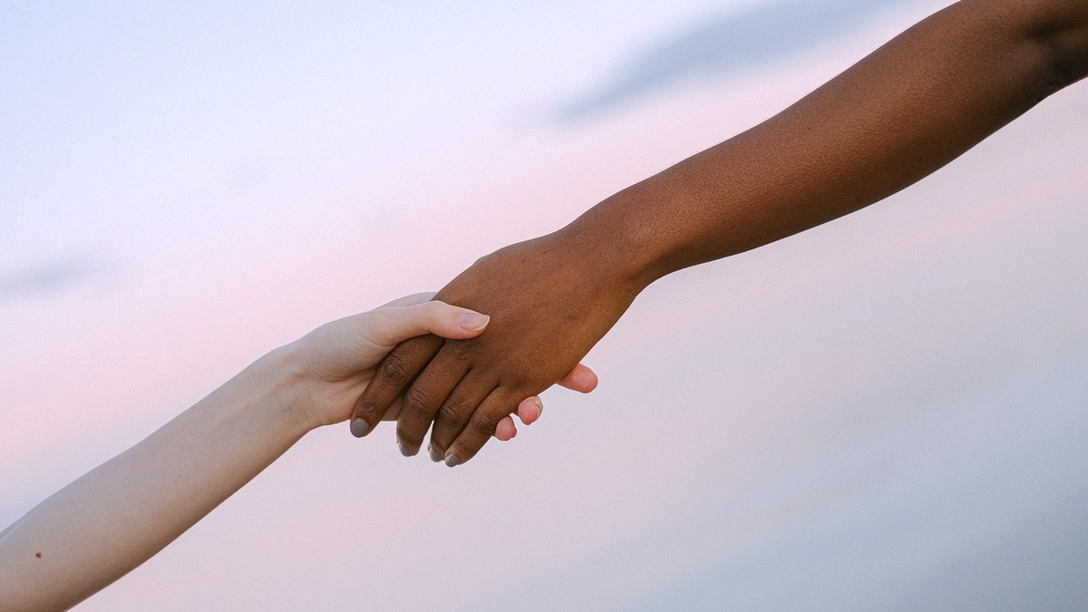 Image of two hands stretching across the screen to embrace.